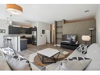 Inviting living room with open floorplan, dark gray kitchen cabinets, and stylish furnishings at 5677 S Park Pl # A102, Englewood, CO 80111
