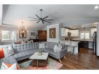 A modern living room with gray sectional sofa, hardwood floors, and an open layout to the kitchen at 5382 S Pine Rd, Evergreen, CO 80439