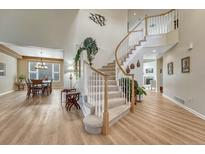 Bright foyer featuring a curved staircase, light hardwood floors, and a view to the adjacent formal dining room at 598 Crossing Cir, Castle Pines, CO 80108