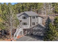 Charming two-story home featuring an attached two-car garage, and mature trees on a beautiful wooded lot at 30455 Telluride Ln, Evergreen, CO 80439