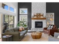 Bright living room features a stone fireplace, modern furnishings and sliding glass door to the outside deck at 30455 Telluride Ln, Evergreen, CO 80439