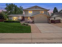 Charming home with a well-manicured lawn, walkway and attached two car garage at dusk at 3138 E Otero Cir, Centennial, CO 80122