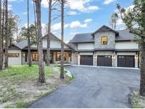 Stunning exterior of a modern luxury home featuring stone accents, a three-car garage, and a well-manicured front yard at 18330 Archers Dr, Monument, CO 80132