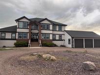 Stately two-story home featuring a three-car garage, brick accents, and a grand entrance with decorative pillars at 897 E Rim Rd, Franktown, CO 80116