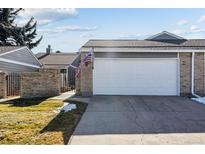 Exterior view of the home's two-car garage with an American flag in the brick facade at 7176 S Vine E Cir, Centennial, CO 80122