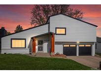 Inviting home exterior featuring a two-car garage, manicured lawn, and natural wood porch supports at dusk at 4484 S Granby Ct, Aurora, CO 80015