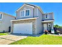 Two-story home with stone accents, gray siding, well-kept lawn, and a two-car garage at 2033 Espana Way, Aurora, CO 80011