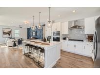 Bright kitchen with white cabinets, a center island with seating, and modern pendant lighting at 15290 W 69Th Pl, Arvada, CO 80007