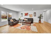 Bright living room features hardwood floors, a large window, and comfortable leather seating around a floral accent rug at 7819 Tejon St, Denver, CO 80221
