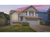 Lovely two-story home with blue shutters, brick accents, and a well-kept front lawn at sunset at 13069 Jackson Dr, Thornton, CO 80241