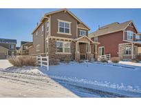 Two-story house with brown siding, stone accents, and a snowy front yard at 1344 S Coolidge Cir, Aurora, CO 80018