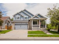 Charming two-story home featuring a covered porch, gray siding and a two car attached garage and landscaped front yard at 15389 E 99Th Way, Commerce City, CO 80022