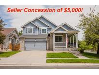 Charming two-story home boasts an inviting front porch, well-manicured lawn, and attached two-car garage at 15389 E 99Th Way, Commerce City, CO 80022