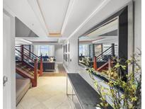 Bright hallway featuring tile floors, tray ceilings, staircase and decorative mirror reflecting the living space at 1891 Curtis St # 1812, Denver, CO 80202