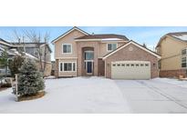 Two-story house with brick and siding, snow-covered lawn, and a two-car garage at 89 Dawn Heath Cir, Littleton, CO 80127