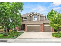 Charming two-story home with three-car garage, well-maintained lawn and brick accents at 15962 W 70Th Dr, Arvada, CO 80007