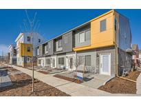 Modern townhome featuring a brick facade and a vibrant yellow accent, complete with a sidewalk at 15345 W 69Th Dr, Arvada, CO 80007