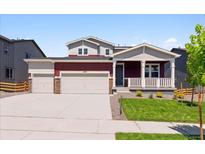 Charming two-story home featuring a covered porch, a three-car garage, and a well-manicured lawn at 1839 Morgan Dr, Erie, CO 80516