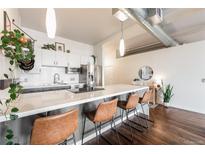Modern kitchen features sleek white cabinets, subway tile backsplash, stainless steel appliances, and a large island with bar seating at 1521 Central St # 2B, Denver, CO 80211