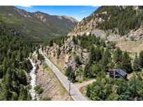 Scenic aerial view of a home nestled in the mountains, surrounded by trees and a flowing river at 205 Loop Dr, Georgetown, CO 80444