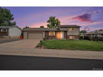 Charming single-Gathering home showcasing a manicured lawn and an attached two-car garage at 6413 W 76Th Ave, Arvada, CO 80003