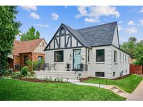 Charming two-story home with blue door, black trim, landscaped yard, and inviting front porch at 1591 Holly St, Denver, CO 80220