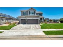 Two-story home featuring a three-car garage, landscaped yard, and a well-maintained lawn at 9716 Uravan St, Commerce City, CO 80022