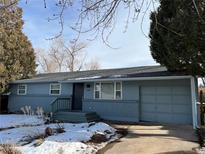 Charming single-story home with a painted blue exterior and a front yard touched by the beauty of winter at 4640 Macky Way, Boulder, CO 80305