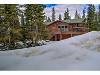 Beautiful log cabin home nestled among evergreens and covered in snow at 492 Kimmes Ln, Breckenridge, CO 80424