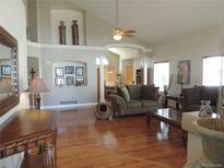 Spacious living room featuring hardwood floors, vaulted ceilings, and decorative architectural shelving at 21024 E 49Th Ave, Denver, CO 80249