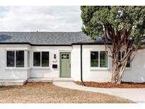 Charming white brick home with a manicured lawn, lush tree, and a welcoming green front door at 4023 E Martin Luther King Jr, Denver, CO 80207
