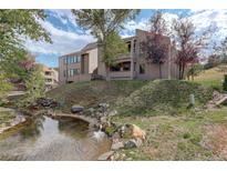 Exterior view of a condo building with a stream and landscaping at 23619 Genesee Village Rd # B, Golden, CO 80401