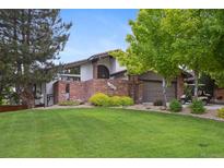 Charming home featuring a brick facade, lush lawn, and mature trees providing shade and curb appeal at 11621 Shoshone Way, Denver, CO 80234