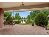 Inviting covered brick patio with a porch swing overlooks a serene pond surrounded by lush greenery at 2800 S University Blvd # 1, Denver, CO 80210