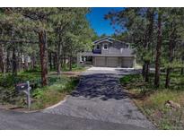 Two-story home with a three-car garage and stone accents surrounded by mature trees at 970 Bend In The Trail Rd, Monument, CO 80132