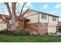Charming two-story home with brick accents, landscaped yard, and inviting front entrance, creating a warm and welcoming curb appeal at 2013 S Holland St, Lakewood, CO 80227