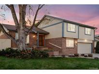 Charming two-story home with brick and siding exterior, lush landscaping, and a cozy front porch at 2013 S Holland St, Lakewood, CO 80227