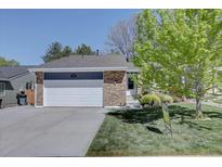 Charming single-story home boasts a brick facade, lush lawn, and a convenient two-car garage at 8745 W Ottawa Ave, Littleton, CO 80128