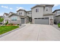 Stunning gray home with stone accents, attached two-car garage, and pristine landscaping at 6912 Sunstrand Ct, Castle Pines, CO 80108
