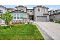 Charming two-story home with a well-manicured lawn, stone accents, and a driveway leading to an attached garage at 6912 Sunstrand Ct, Castle Pines, CO 80108
