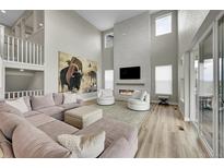 Spacious living room boasts a fireplace, light wood floors, and large windows at 6912 Sunstrand Ct, Castle Pines, CO 80108