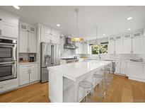 Bright, modern kitchen features white cabinetry, stainless steel appliances, and a large center island with seating at 5853 S Havana Ct, Englewood, CO 80111
