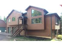 Two-story house with wood siding, stairs leading to the front door, and unique geometric windows at 9274 Sandy Ln, Conifer, CO 80433