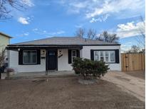 Charming single-story home featuring white siding, black trim, a well-kept lawn, and a welcoming front porch at 6690 E 72 Pl, Commerce City, CO 80022
