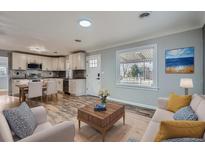 Bright, open living room and dining area features wood floors and modern kitchen with updated appliances at 6690 E 72 Pl, Commerce City, CO 80022