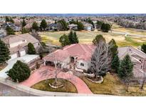 Expansive home with red tile roof, mature trees, circular driveway, and golf course community at 7022 Secrest Ct, Arvada, CO 80007