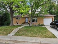 Brick ranch home with a grassy yard, trees, and a carport at 348 Emery Rd, Northglenn, CO 80233