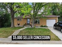 Charming brick home features an attached garage, landscaped yard, and a relaxing hammock hanging from a mature shade tree at 348 Emery Rd, Northglenn, CO 80233
