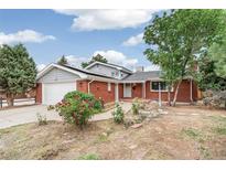 Charming red brick house featuring a well-manicured front yard and an attached garage at 206 Troy St, Aurora, CO 80011