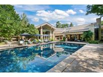 Stunning pool area with lounge chairs, umbrellas, and views of the home's architecture surrounded by lush landscaping at 4766 S Fillmore Ct, Cherry Hills Village, CO 80113